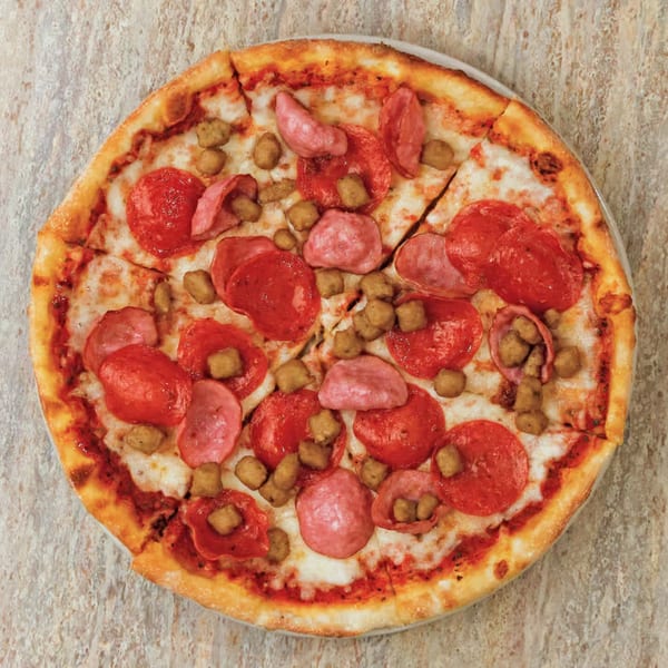 Pastafina's pepperoni, sausage, and ham pizza, sliced and ready to eat.