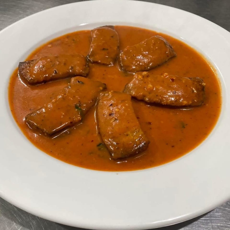Pastafina's Italian dish features six pieces of meat in a rich, reddish-orange sauce on a white plate.