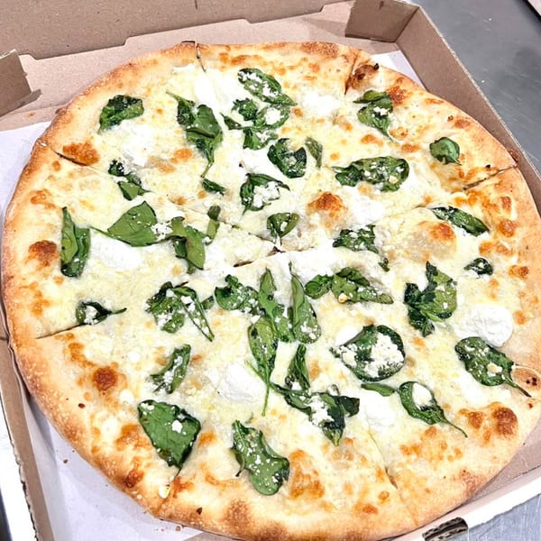 Pastafina's white pizza with spinach and ricotta cheese in a cardboard delivery box.